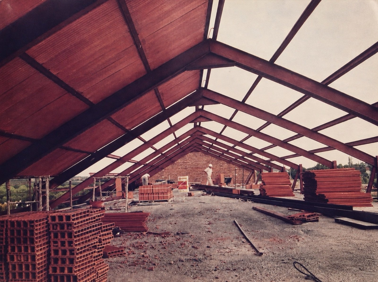 Interior de la cubierta con cerchas metálicas y operarios en la Casa de la Cultura de Nuevo Baztán