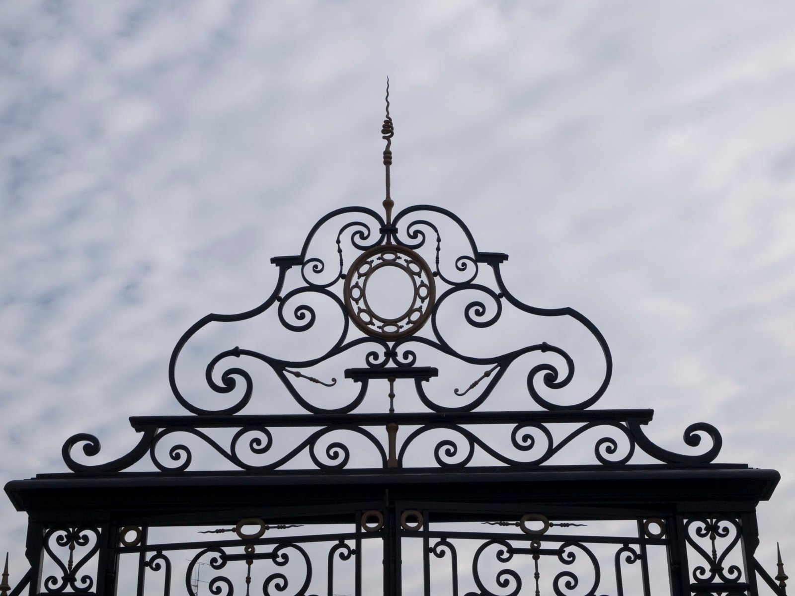 Detalle en primer plano del copete superior ornamental en hierro forjado de la Puerta del Niño Jesús